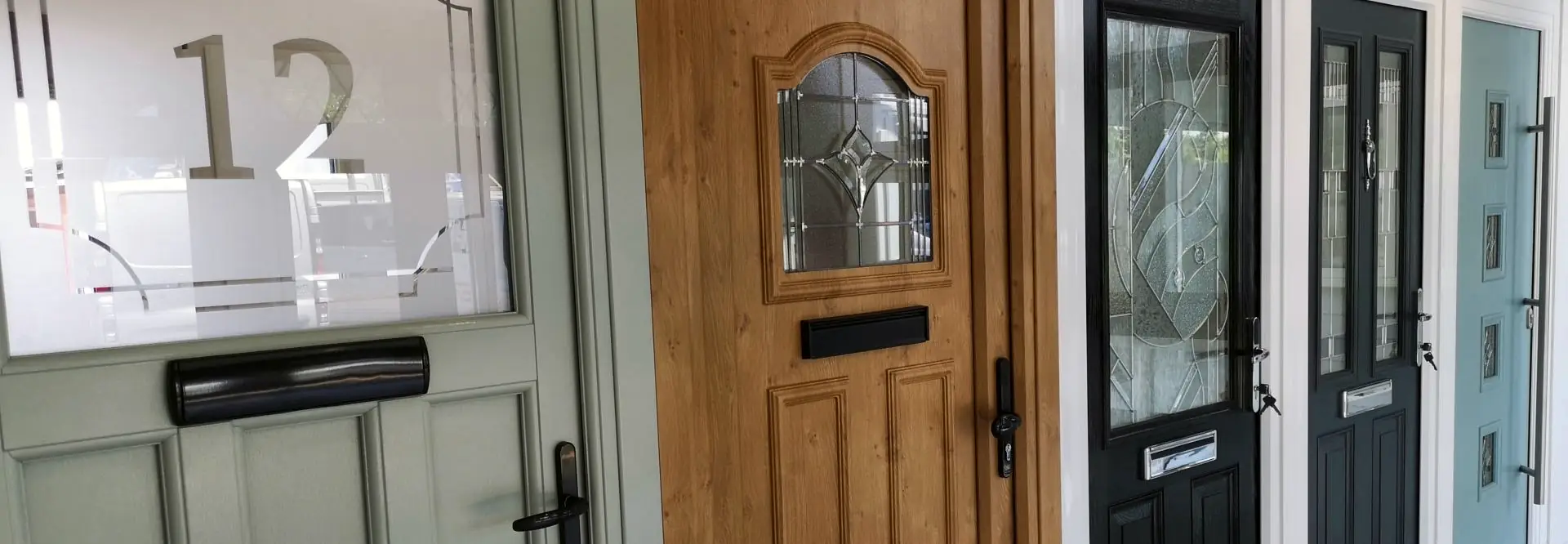 The Admiral showroom door wall: sage, golden oak, black and duck-egg front doors with decorative glass, side by side.