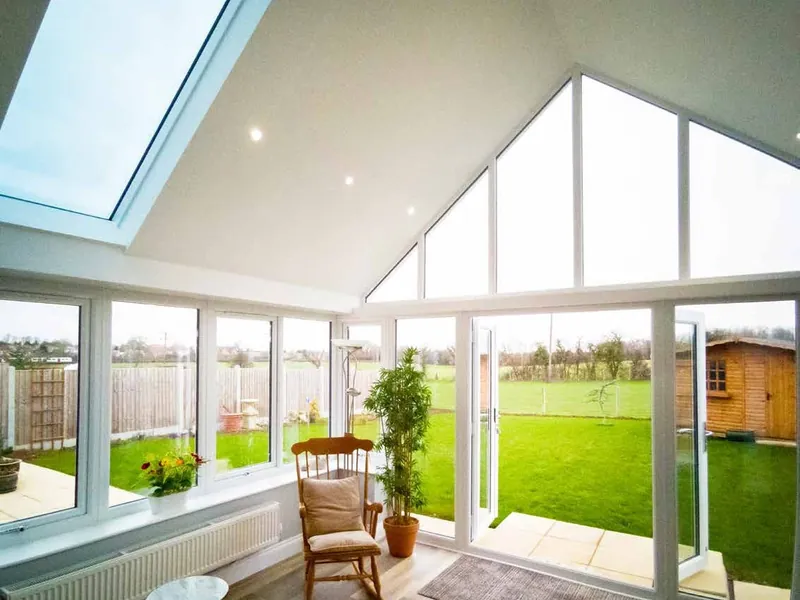 Inside a conservatory under a tiled Ultraroof, with a plastered, vaulted ceiling and long glass panels in the roof.